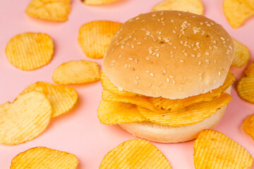 Hamburger with ribbed chips on a pink background.