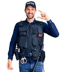 Young handsome man wearing police uniform smiling and confident gesturing with hand doing small size sign with fingers looking and the camera. measure concept.
