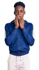 Young african american man wearing sportswear laughing and embarrassed giggle covering mouth with...