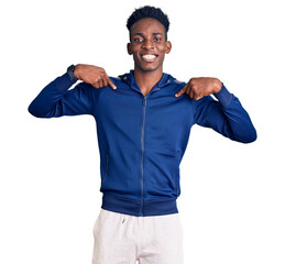 Fototapeta premium Young african american man wearing sportswear looking confident with smile on face, pointing oneself with fingers proud and happy.