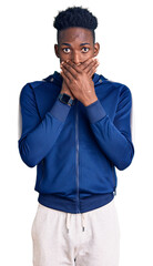 Young african american man wearing sportswear shocked covering mouth with hands for mistake. secret concept.