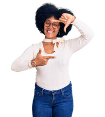 Young african american girl wearing casual clothes and glasses smiling making frame with hands and fingers with happy face. creativity and photography concept.