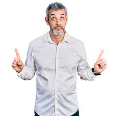 Middle age hispanic with grey hair wearing casual white shirt pointing up looking sad and upset,...