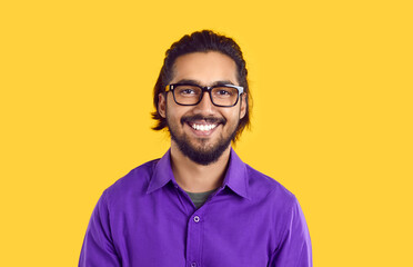 Portrait of happy young Indian man wearing classic eyeglasses on orange background. Close up of...