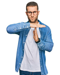 Young caucasian man wearing casual clothes doing time out gesture with hands, frustrated and...
