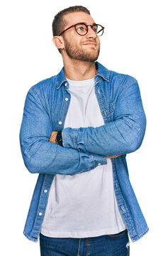Young caucasian man wearing casual clothes looking to the side with arms crossed convinced and confident