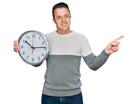 Handsome young man holding big clock smiling happy pointing with hand and finger to the side