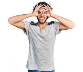 Young hispanic man wearing casual t shirt doing ok gesture like binoculars sticking tongue out, eyes looking through fingers. crazy expression.