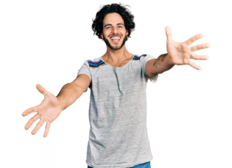 Young hispanic man wearing casual t shirt looking at the camera smiling with open arms for hug. cheerful expression embracing happiness.