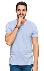 Young hispanic man wearing casual clothes looking confident at the camera smiling with crossed arms and hand raised on chin. thinking positive.