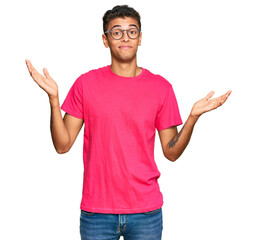 Young handsome african american man wearing casual clothes clueless and confused expression with...