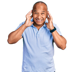 Fototapeta premium Hispanic middle age man wearing casual t shirt covering ears with fingers with annoyed expression for the noise of loud music. deaf concept.