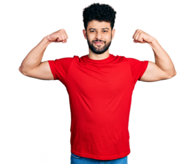 Young arab man with beard wearing casual red t shirt showing arms muscles smiling proud. fitness concept.
