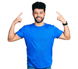 Young arab man with beard wearing casual blue t shirt smiling pointing to head with both hands finger, great idea or thought, good memory