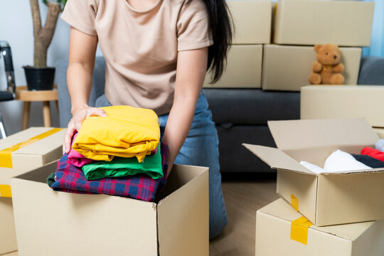 The young woman is folding clothes and putting them in boxes in preparation for moving into her new house