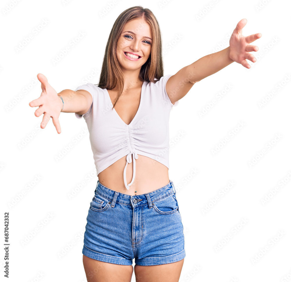 Wall mural young beautiful blonde woman wearing casual white tshirt looking at the camera smiling with open arm