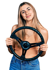 Hispanic young woman holding steering wheel relaxed with serious expression on face. simple and...