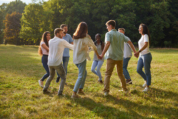 Group of cheerful joyful friends having fun in beautiful summer park. Happy young diverse...