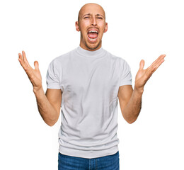 Naklejka premium Bald man with beard wearing casual white t shirt crazy and mad shouting and yelling with aggressive expression and arms raised. frustration concept.