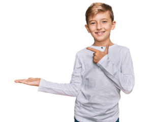 Little caucasian boy kid wearing casual clothes amazed and smiling to the camera while presenting with hand and pointing with finger.
