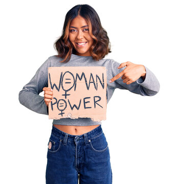 Young beautiful mixed race woman holding woman power banner smiling happy pointing with hand and finger