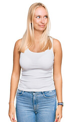 Fototapeta premium Young blonde girl wearing casual style with sleeveless shirt smiling looking to the side and staring away thinking.