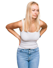 Young blonde girl wearing casual style with sleeveless shirt suffering of backache, touching back with hand, muscular pain