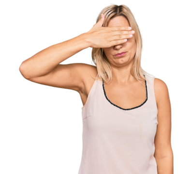 Middle age caucasian woman wearing casual clothes covering eyes with hand, looking serious and sad. sightless, hiding and rejection concept