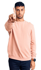 Young hispanic man wearing casual clothes pointing with finger up and angry expression, showing no gesture