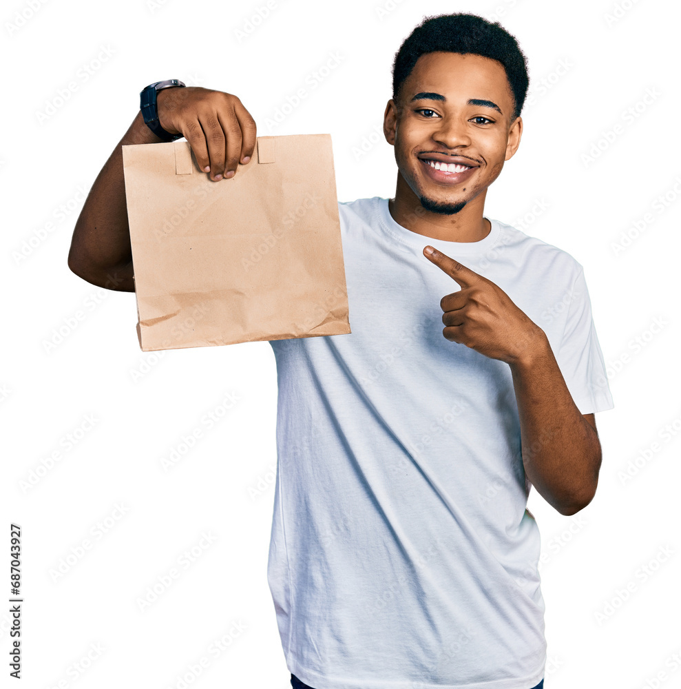 Wall mural young african american man holding take away paper bag smiling happy pointing with hand and finger