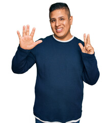 Fototapeta premium Young latin man wearing casual clothes showing and pointing up with fingers number eight while smiling confident and happy.