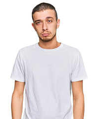 Fototapeta premium Hispanic young man wearing casual white t shirt depressed and worry for distress, crying angry and afraid. sad expression.