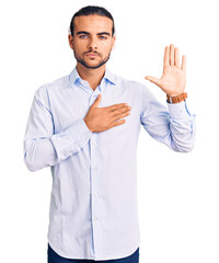 Young handsome man wearing business clothes swearing with hand on chest and open palm, making a...