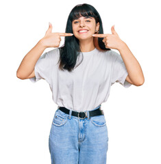 Young hispanic girl wearing casual clothes smiling cheerful showing and pointing with fingers teeth...