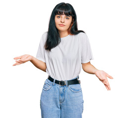Young hispanic girl wearing casual clothes clueless and confused expression with arms and hands raised. doubt concept.