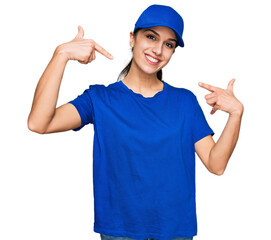 Young hispanic girl wearing delivery courier uniform smiling cheerful showing and pointing with fingers teeth and mouth. dental health concept.