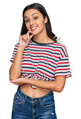 Young hispanic girl wearing casual clothes looking confident at the camera with smile with crossed arms and hand raised on chin. thinking positive.