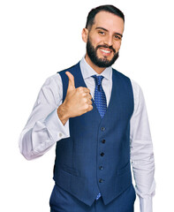 Young man with beard wearing business vest doing happy thumbs up gesture with hand. approving expression looking at the camera showing success.