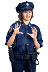 Young beautiful girl wearing police uniform disgusted expression, displeased and fearful doing...