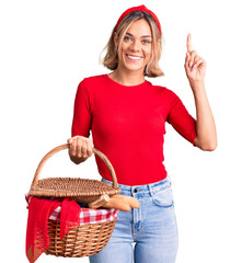 Beautiful caucasian woman holding picnic wicker basket with bread surprised with an idea or...