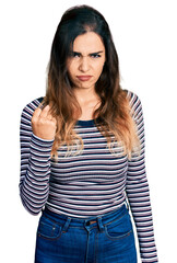 Beautiful hispanic woman wearing casual striped shirt angry and mad raising fist frustrated and furious while shouting with anger. rage and aggressive concept.