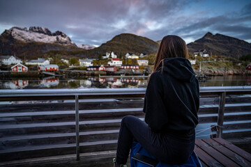 young woman drinking coffee in the morning and taking a look on the bay in Sørvågen fisherman...