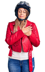 Young beautiful woman wearing motorcycle helmet smiling with hands on chest with closed eyes and grateful gesture on face. health concept.