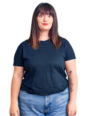 Fototapeta premium Young plus size woman wearing casual clothes puffing cheeks with funny face. mouth inflated with air, crazy expression.