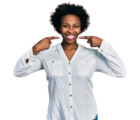 African american woman with afro hair wearing casual white t shirt smiling cheerful showing and pointing with fingers teeth and mouth. dental health concept.