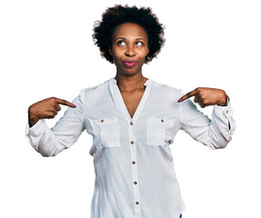 African american woman with afro hair pointing with fingers to herself smiling looking to the side...
