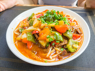 Stewed vegetables, tomatoes, peppers with beef on a plate in a restaurant