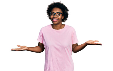 African american woman with afro hair wearing casual clothes and glasses clueless and confused expression with arms and hands raised. doubt concept.