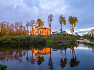 Fototapeta premium The old Orthodox church on the shore of the lake at sunset