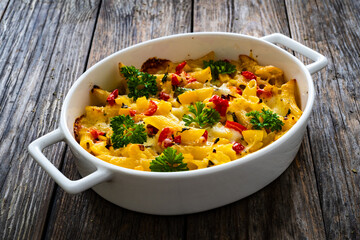 Noodle casserole with mozzarella cheese and vegetables on wooden table
